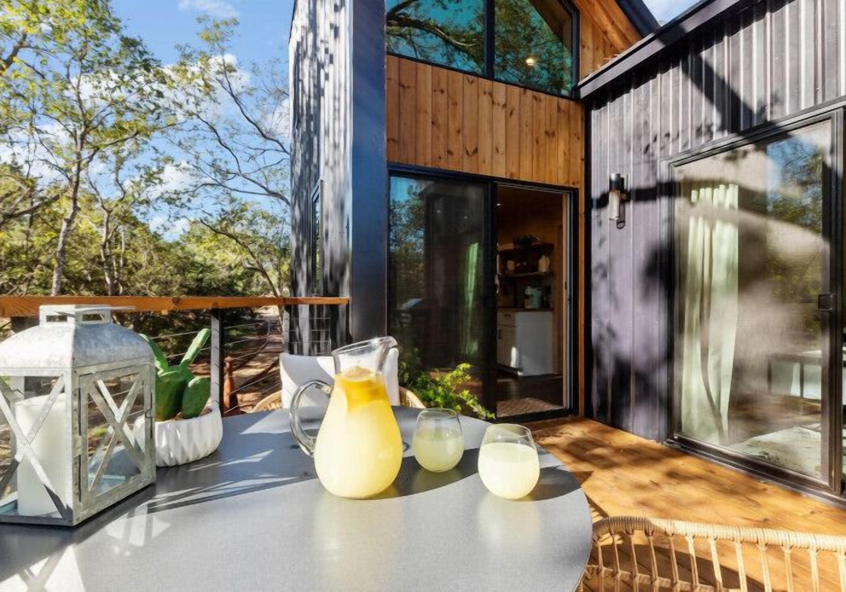 A modern outdoor seating area with a table, a pitcher of lemonade, and a lantern.