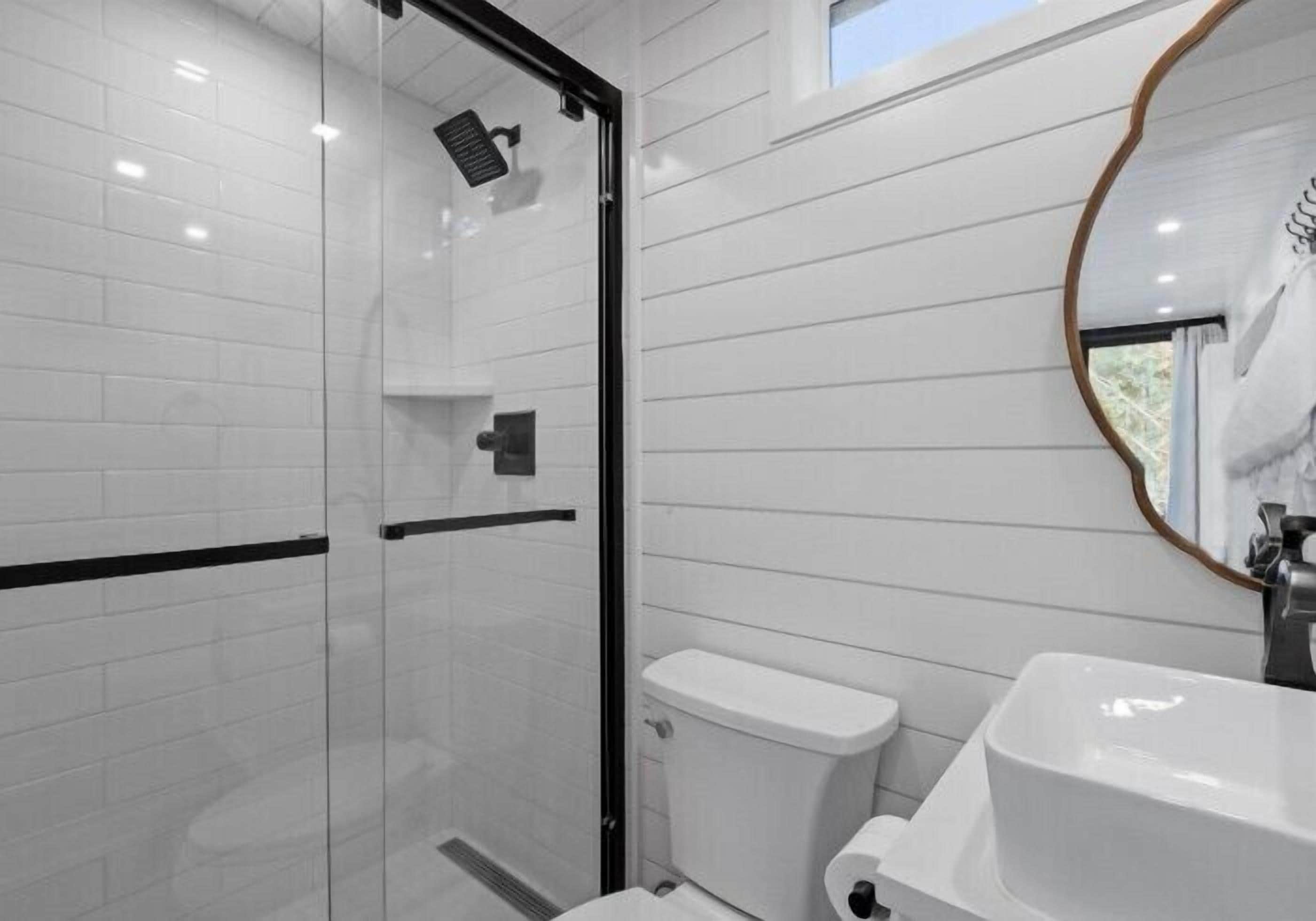 A modern bathroom with a glass shower enclosure, a white toilet, and a sink with a mirror.