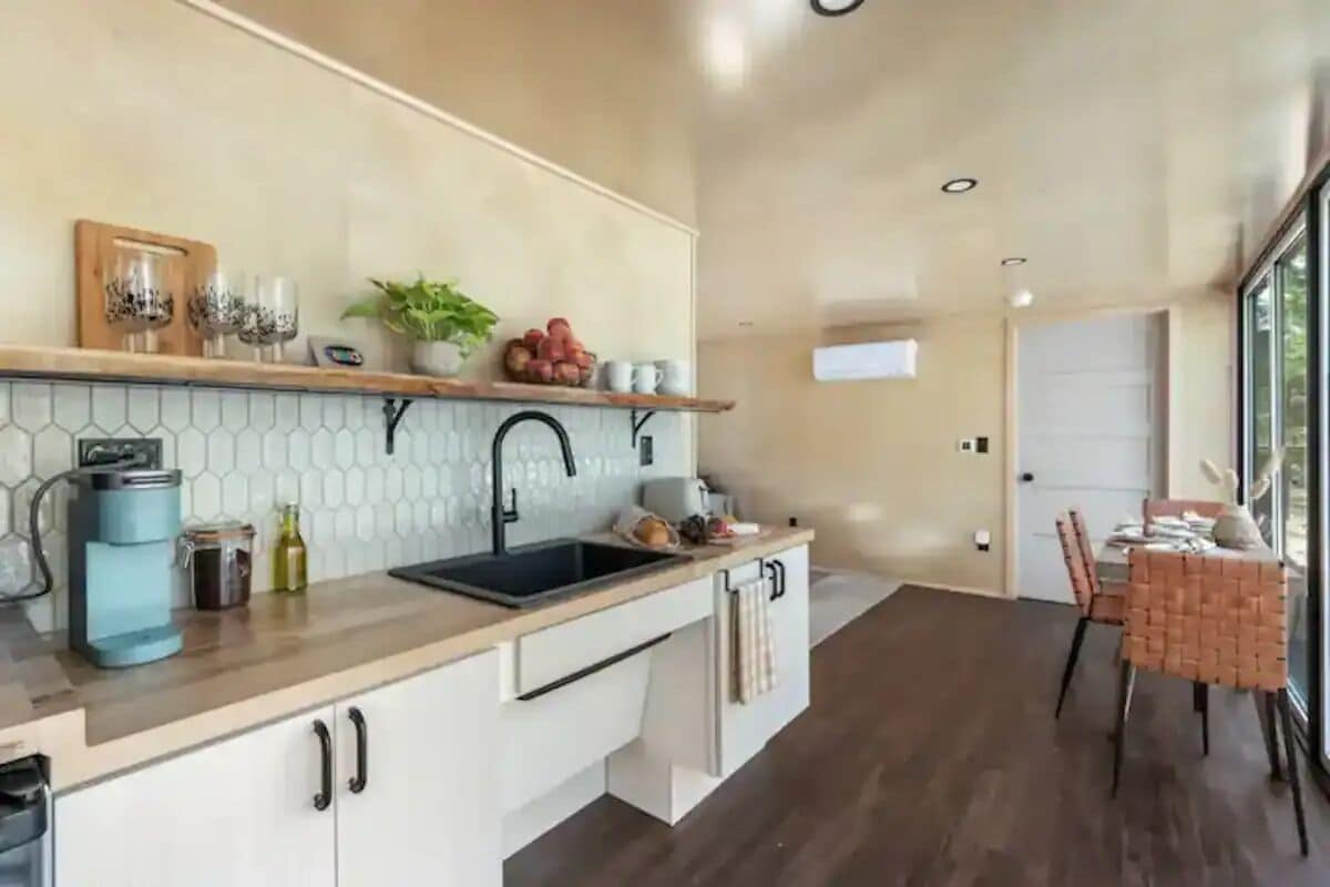 A modern kitchen with a wooden countertop, a sink, and a dining area with a table and chairs.