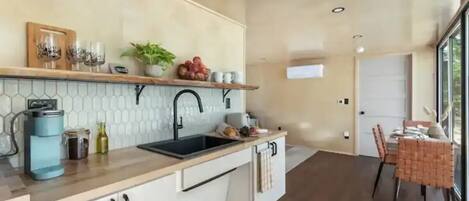 Una cocina moderna con encimera de madera, un fregadero y una zona de comedor con mesa y sillas.
