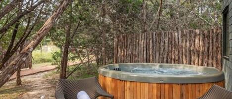 A hot tub surrounded by wicker chairs and a table with snacks and glasses.