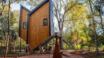 Una cabaña moderna de madera con un diseño triangular distintivo, rodeada de un bosque.