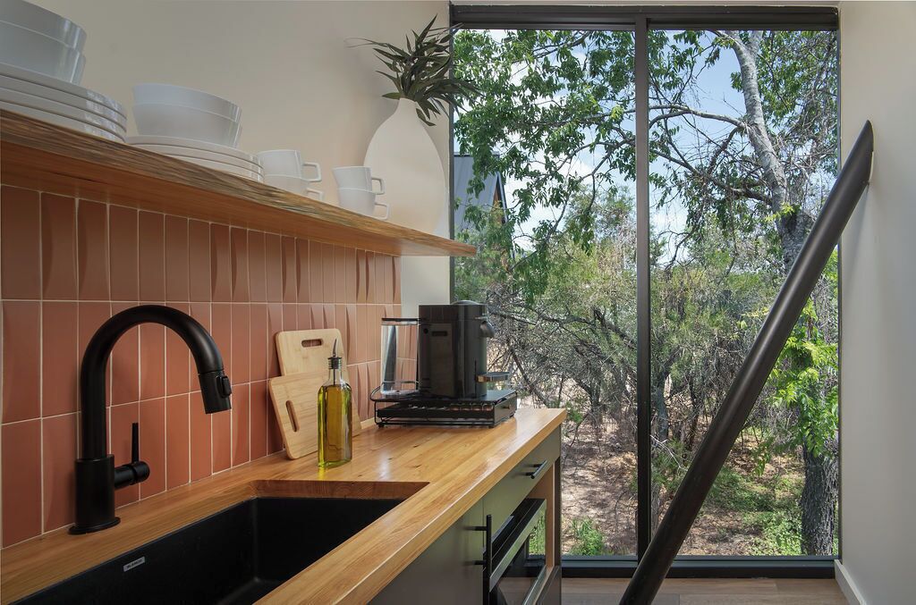 Una cocina moderna con encimera de madera, un grifo negro y una cafetera.