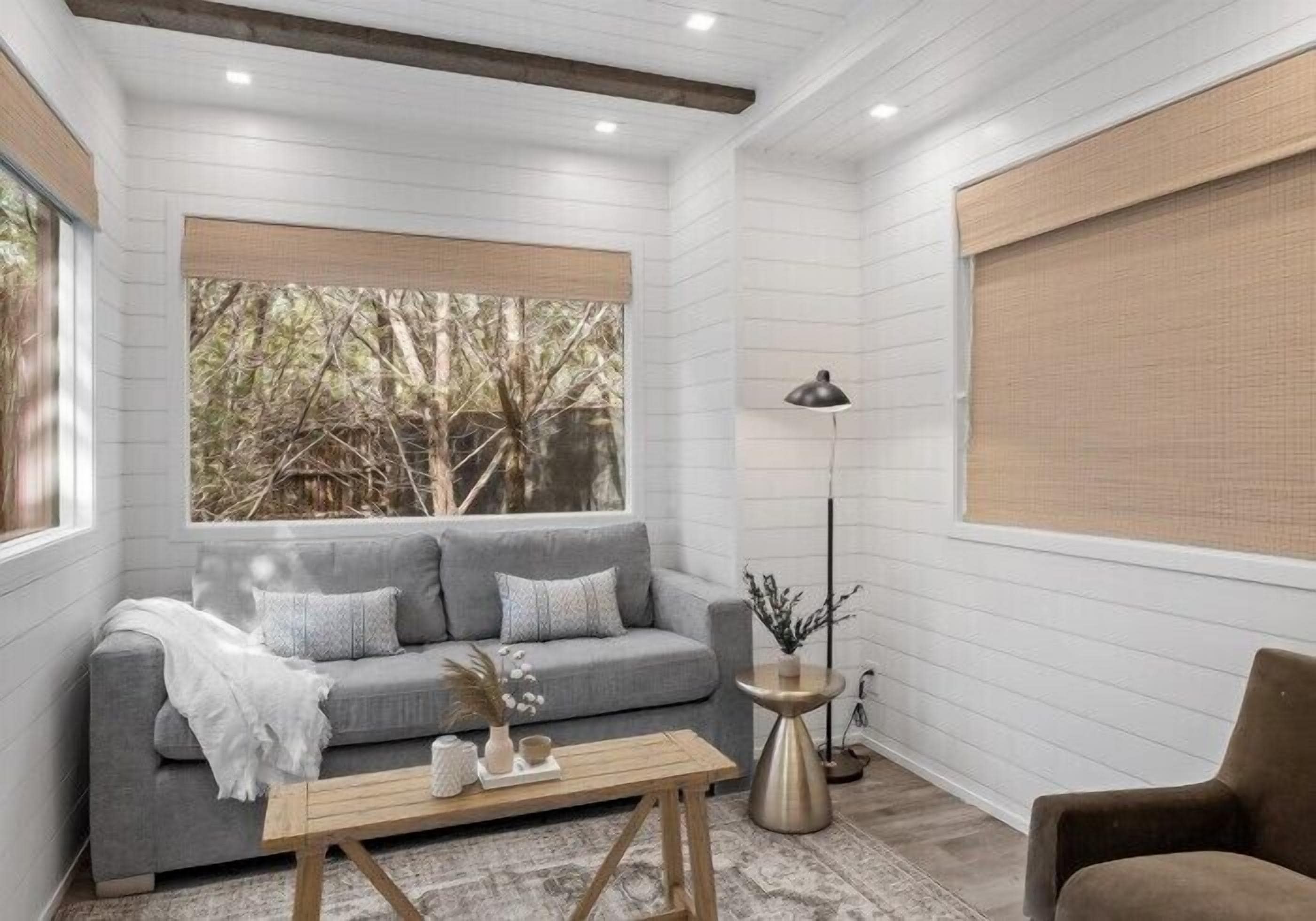 Un salon moderne avec un canapé gris, une table basse en bois et un lampadaire.