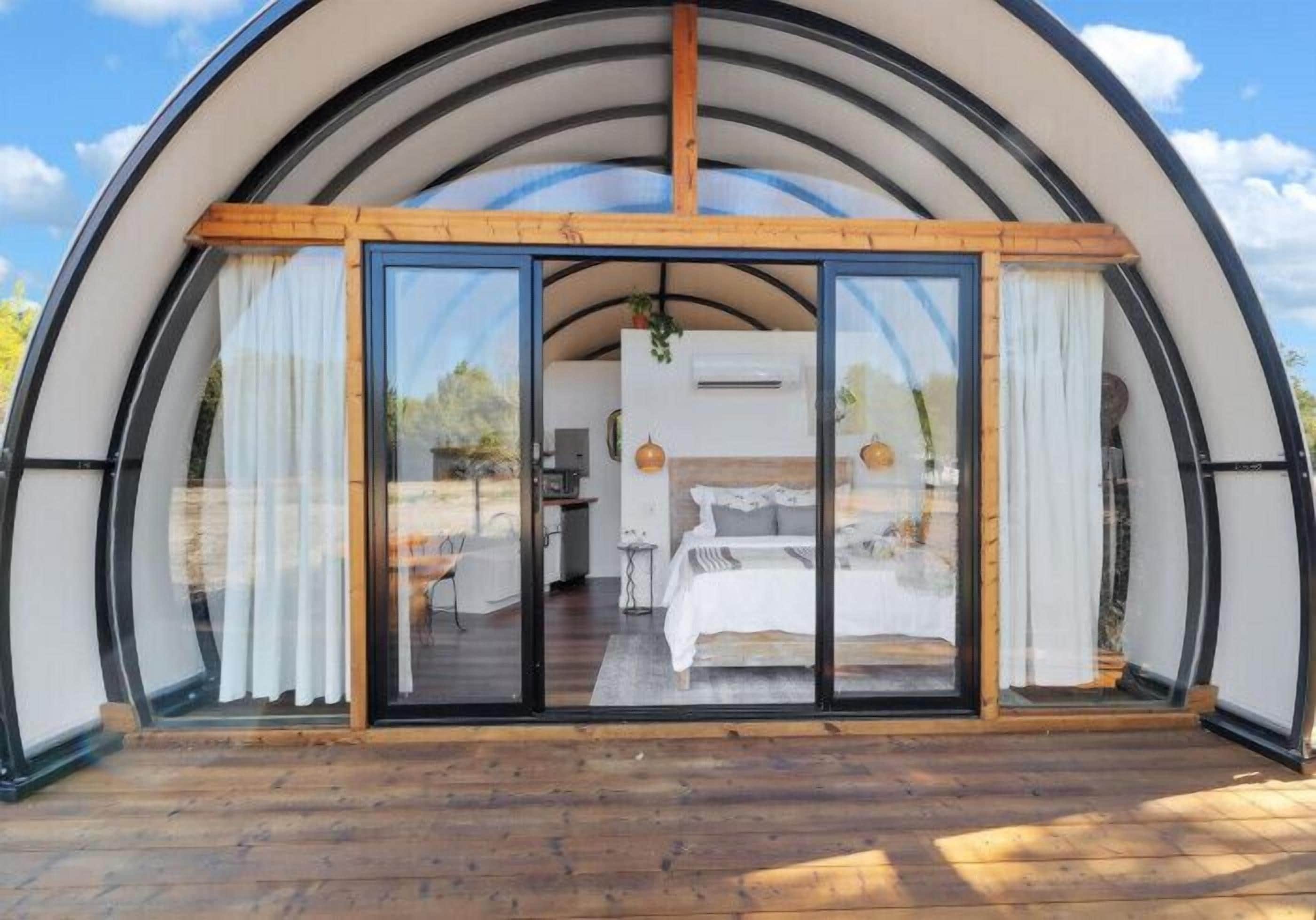 A dome-shaped structure with a bedroom visible through large glass doors.