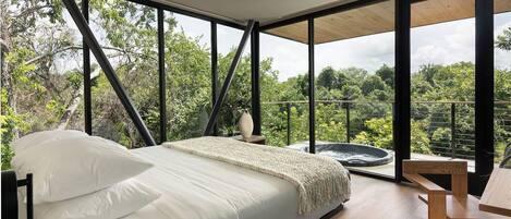 Un dormitorio con una cama grande, una mesa de madera y vistas al exterior.
