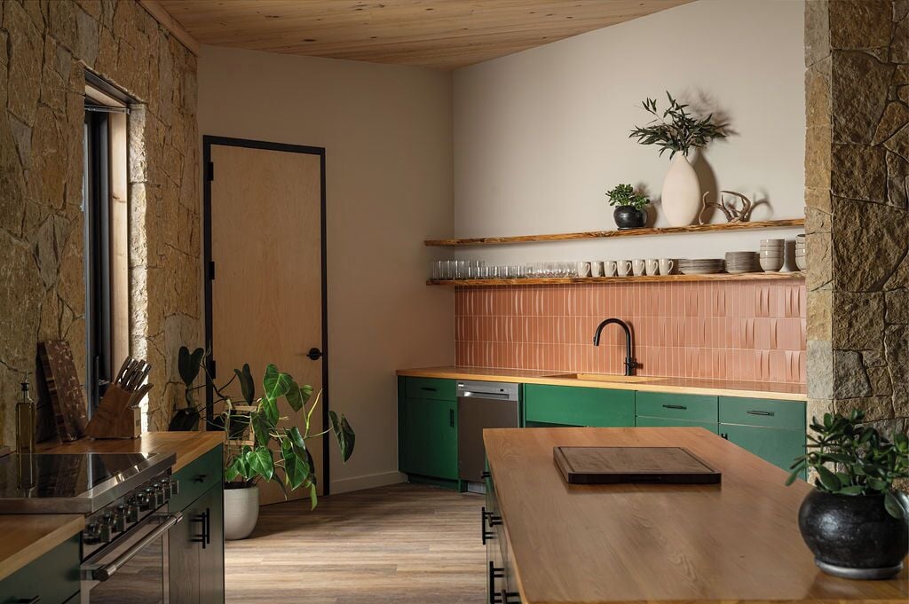 A compact kitchen with a stone wall, wooden cabinets, and a green countertop.