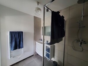 Une salle de bain avec une douche, un lavabo et un porte-serviettes.