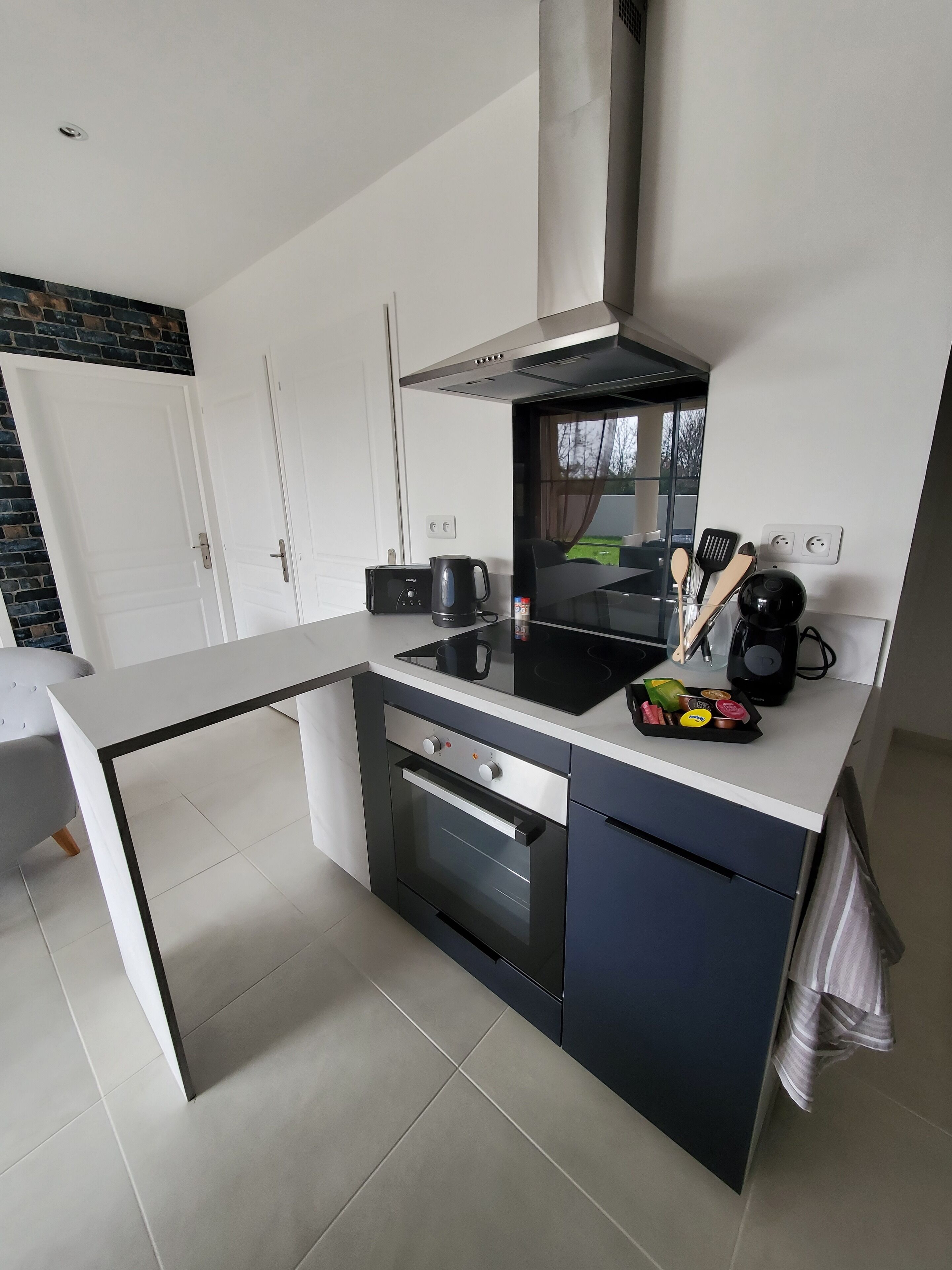 A modern kitchen with a black stove, white cabinets, and a glass dining table.