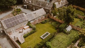 A traditional stone house with a spacious backyard, a small garden, and a solar panel. - Four Season's Splendor: Artist's Nest beside Walled Garden on Seaside Estate (Portpatrick)