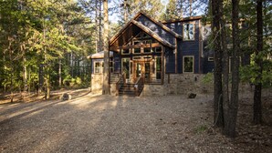 Un chalet rustique avec des fondations en pierre, des poutres en bois et de grandes fenêtres.