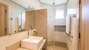 A modern bathroom with a large sink, a mirror, and a shower area. - Taua Resort & Convention Caete (Caete)