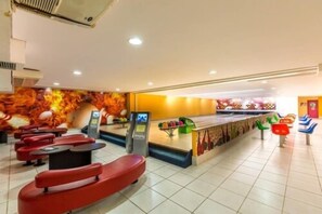 A modern indoor space with red seating, a counter with a colorful mural, and a tiled floor.