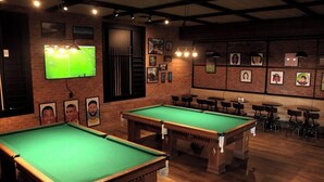 A billiards room with two pool tables, a television, and framed pictures on the walls. - Taua Resort & Convention Caete (Caete)