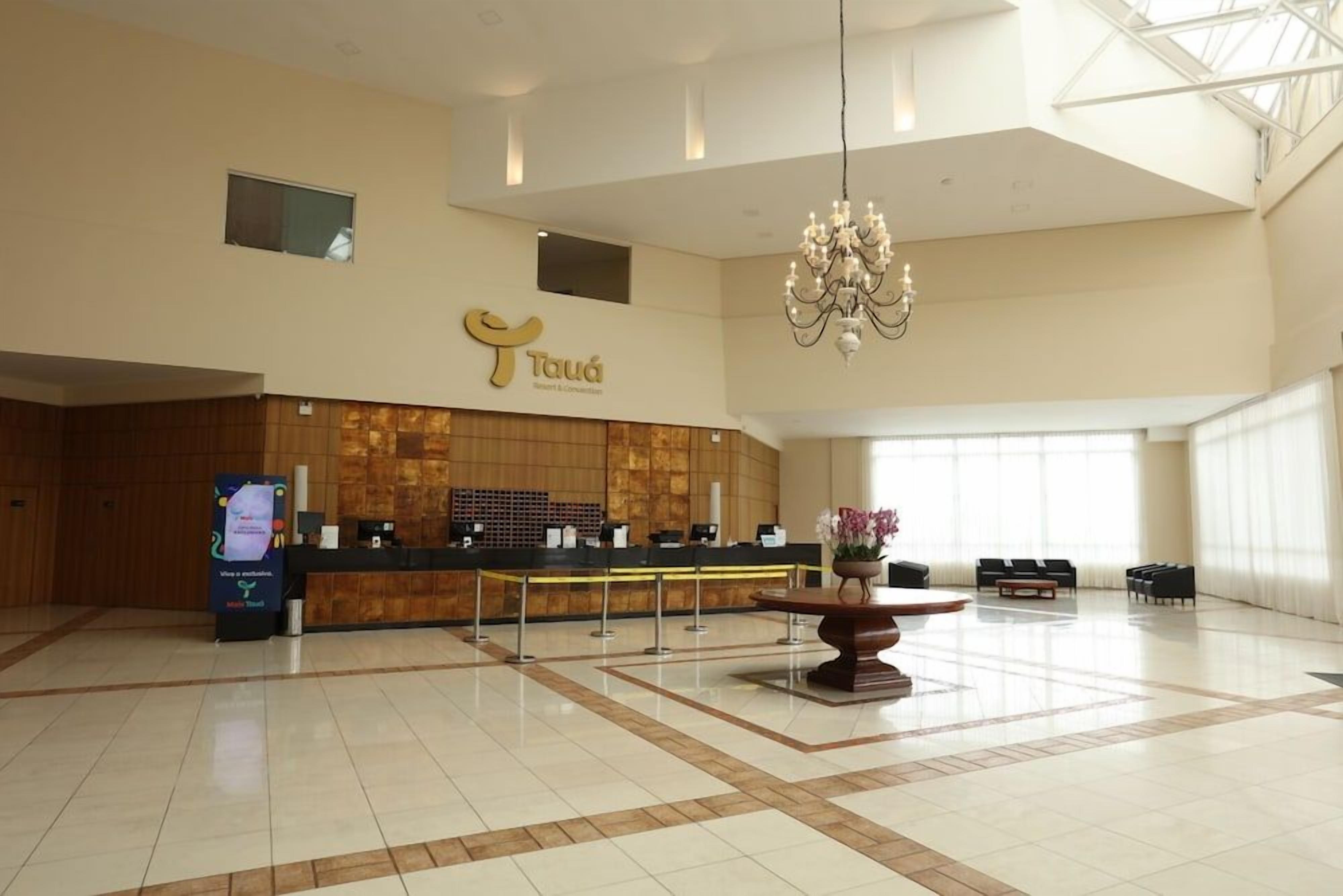 A spacious lobby with a reception desk, a chandelier, and a seating area.