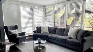 Una sala moderna con un sofá seccional gris oscuro, un sillón negro y una mesa de centro redonda con un objeto decorativo.