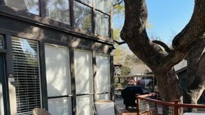 Una terraza de madera con mobiliario de mimbre y un árbol grande.