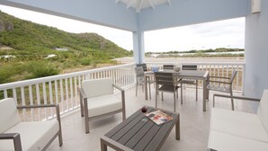 A covered outdoor seating area with a view of a hillside and beach. - Close to beach. Peaceful location. Private pool. (St Mary's)