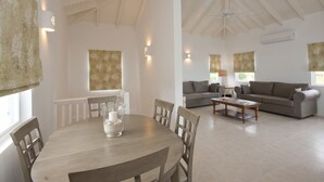 A spacious living area with a round wooden table, two sofas, and a ceiling fan. - Close to beach. Peaceful location. Private pool. (St Mary's)