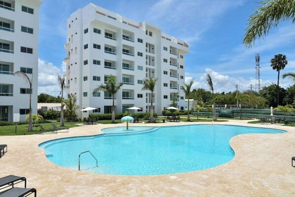 Un hôtel moderne doté d’une piscine, de palmiers et surplombant un ciel d’un bleu limpide.