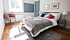 A bedroom with a bed, a chair, a nightstand, a lamp, and a window. - Traditional Connemara Retreat | 5 Mins to Aran Ferry (Co. na Gaillimhe)