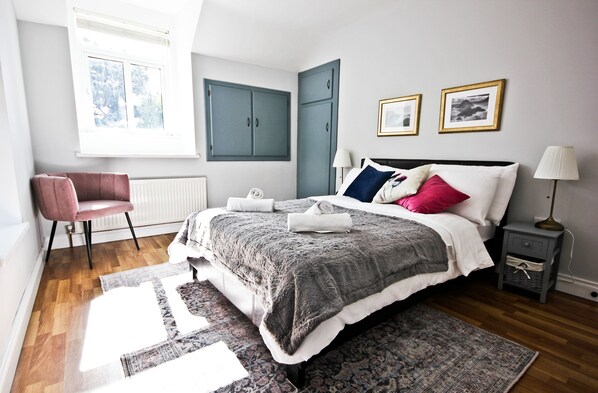 A bedroom with a bed, a chair, a nightstand, a lamp, and a window. - Traditional Connemara Retreat | 5 Mins to Aran Ferry (Co. na Gaillimhe)