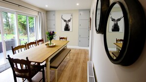A dining area with a wooden table, chairs, and a bench. There are two framed deer head pictures on the wall. - Traditional Connemara Retreat | 5 Mins to Aran Ferry (Co. na Gaillimhe)