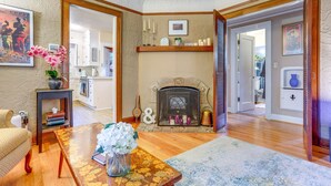 A cozy living room with a fireplace, wooden furniture, and a view into another room. - 1 Mi to Park & Waterfront! Seattle Home w/ Balcony (Seattle)