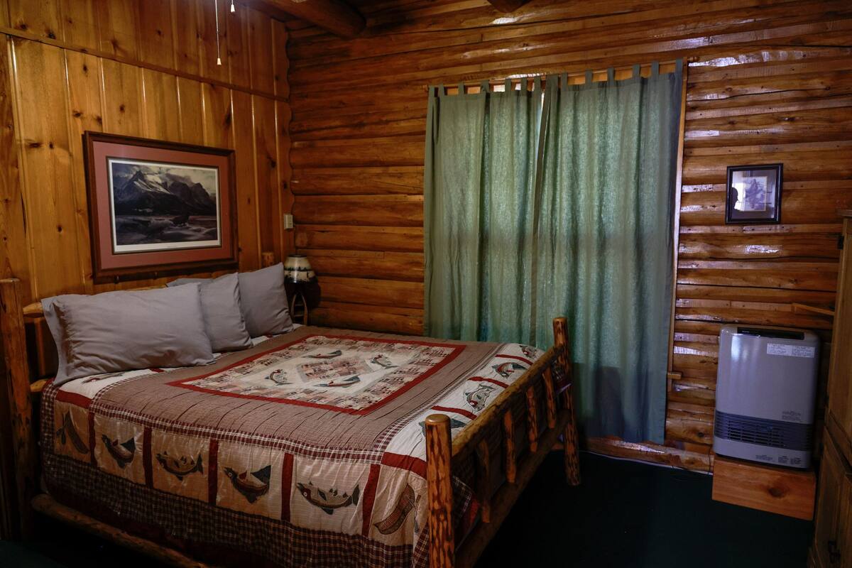 Une pièce de style cabane en bois, avec un lit, un tableau encadré au mur et un radiateur.