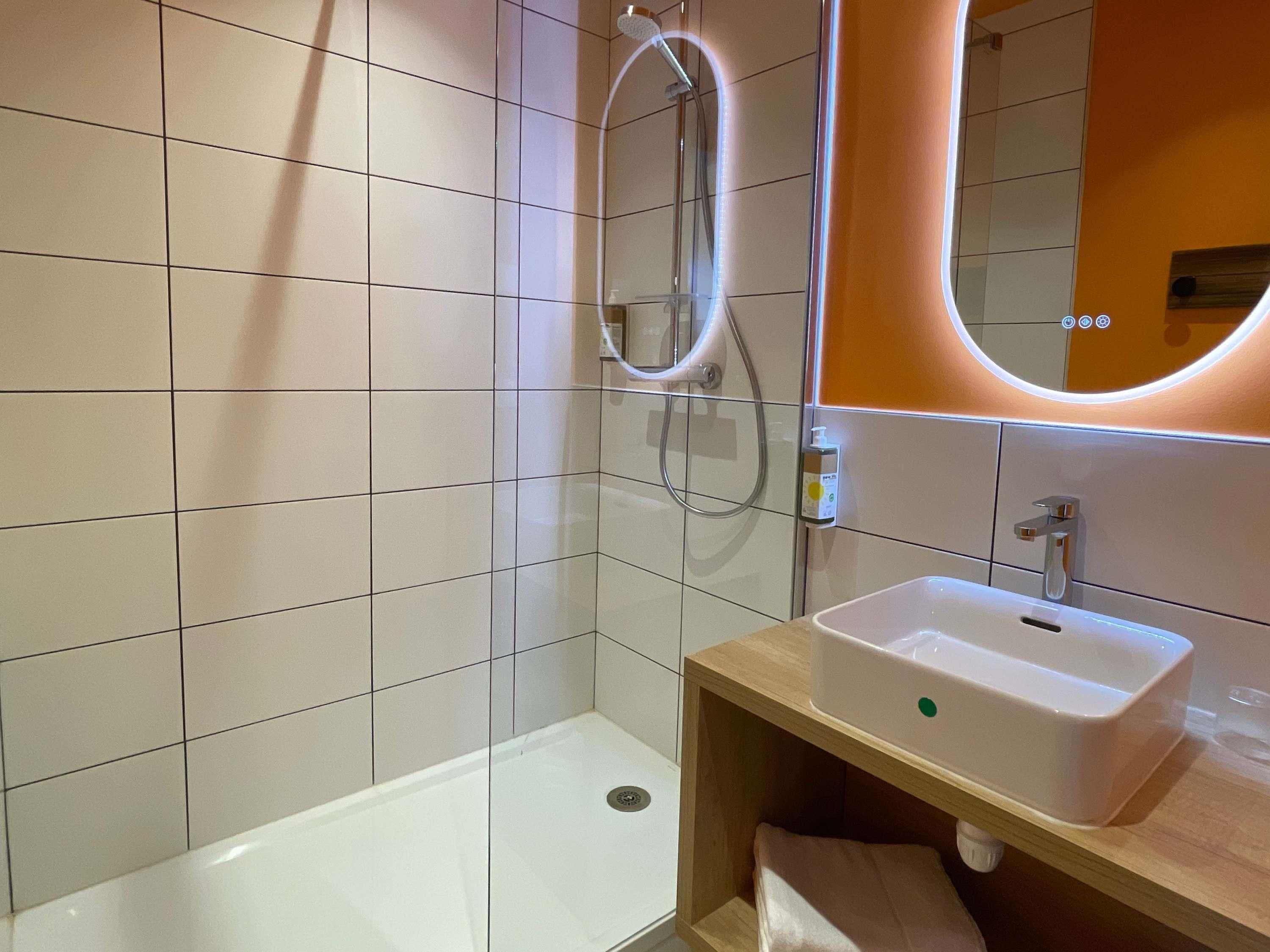 A modern bathroom with a shower, a sink, and a mirror.