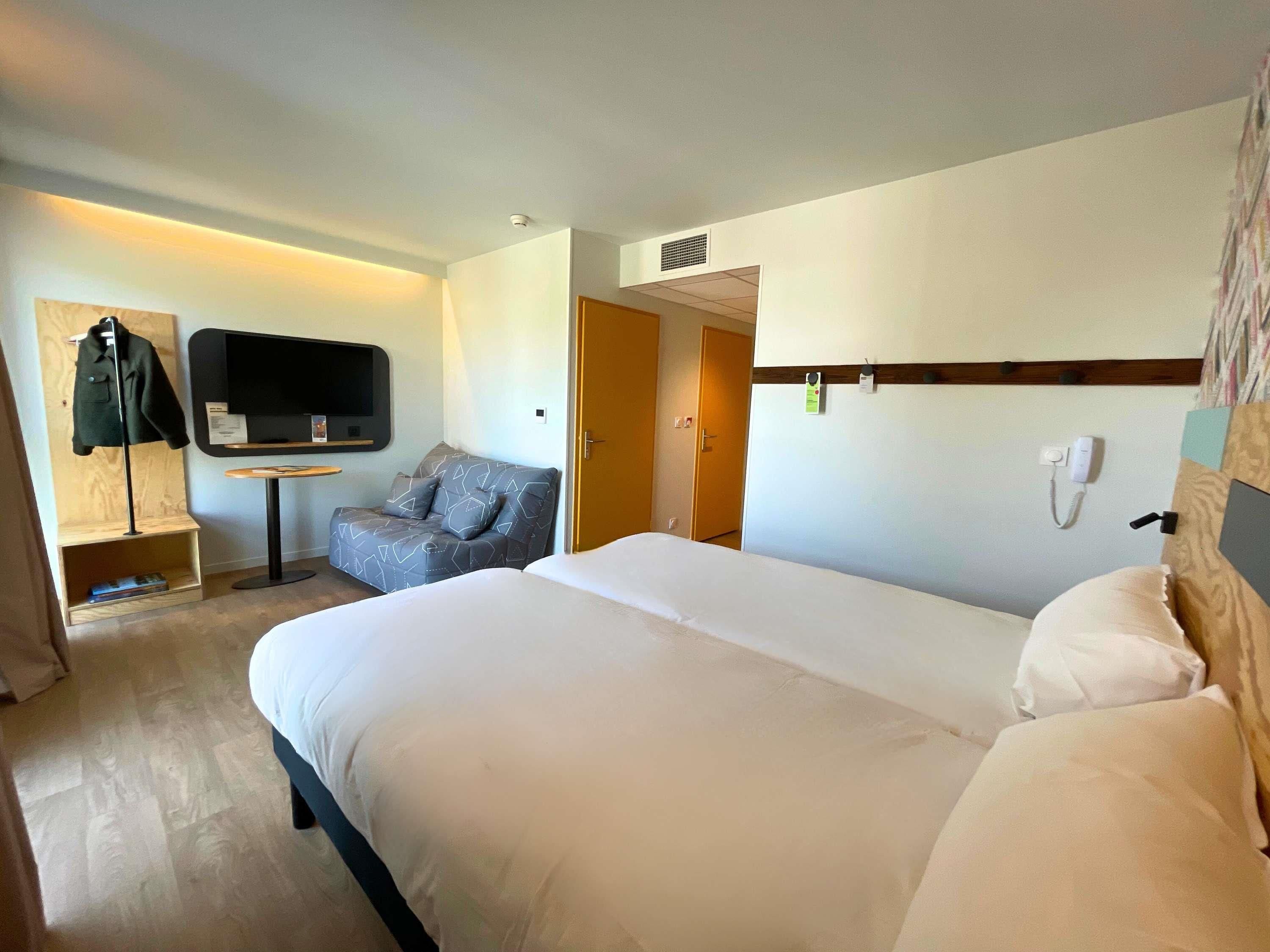 Een hotelkamer met een groot bed, een bank, een televisie en een bureau.