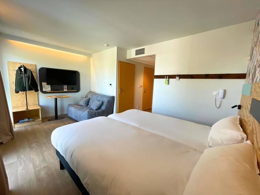 Une chambre d’hôtel avec un grand lit, un canapé, une télévision et un bureau.