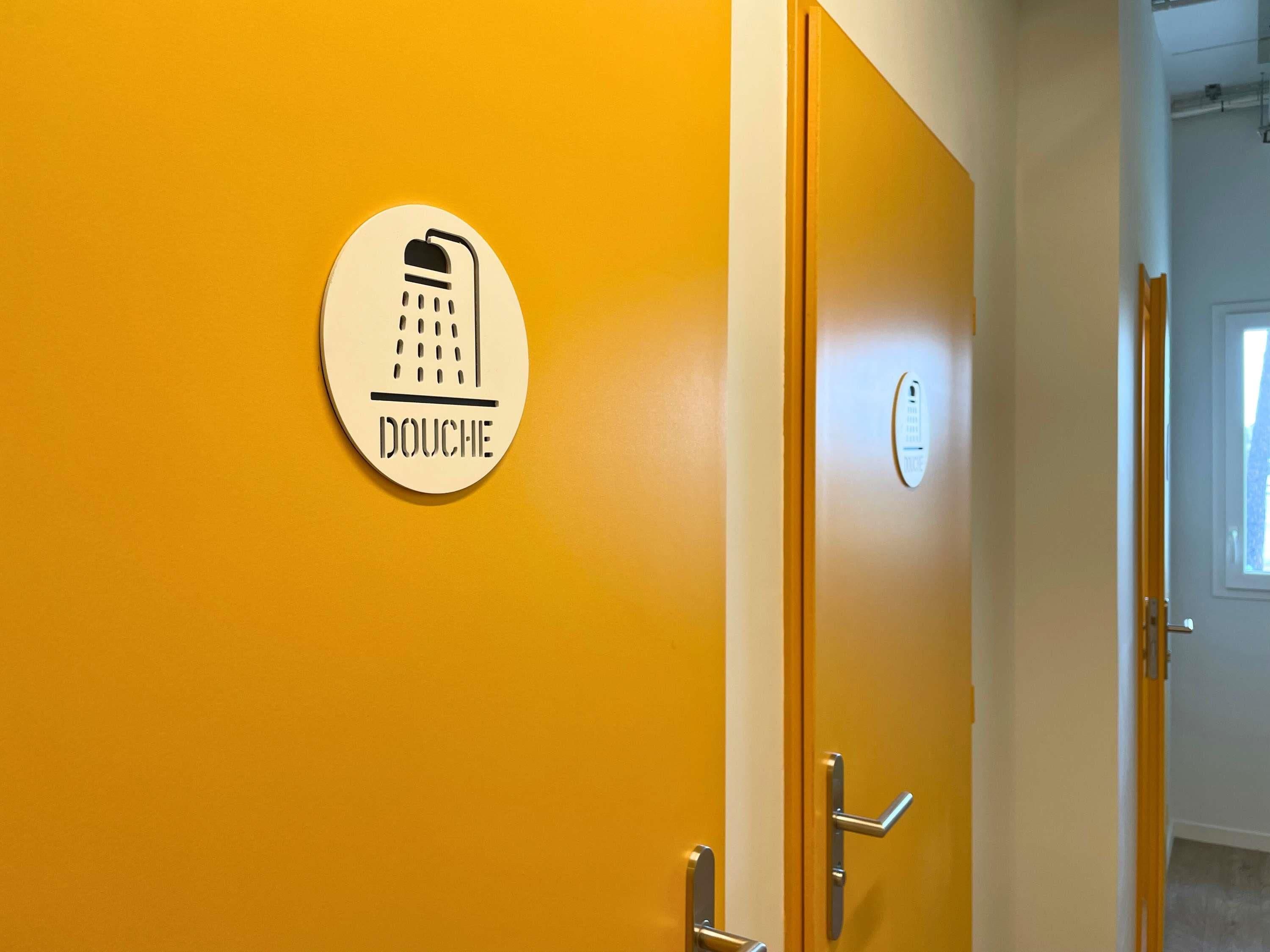 Porta di una camera d'hotel con un'indicazione per la doccia e un termostato.