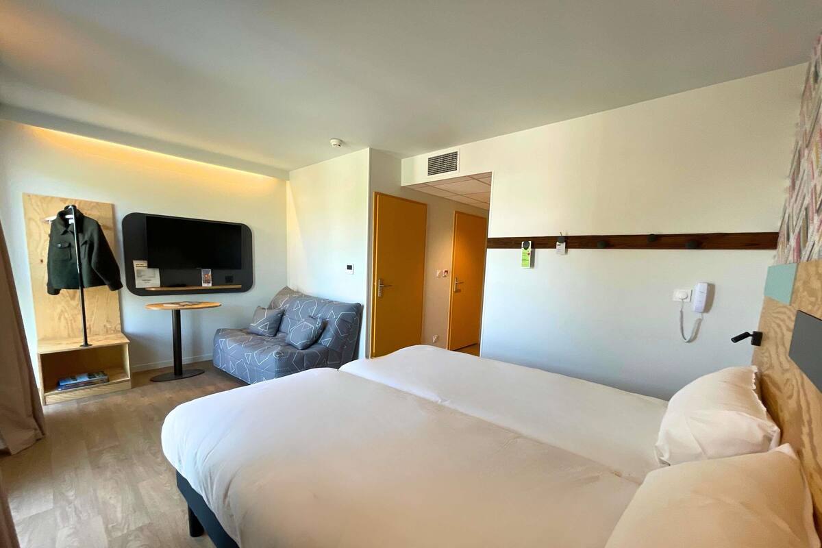 A hotel room with a large bed, a sofa, a TV, and a desk.