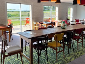 Un espace repas avec des tables et des chaises, de grandes fenĂȘtres et une vue sur lâextĂ©rieur.