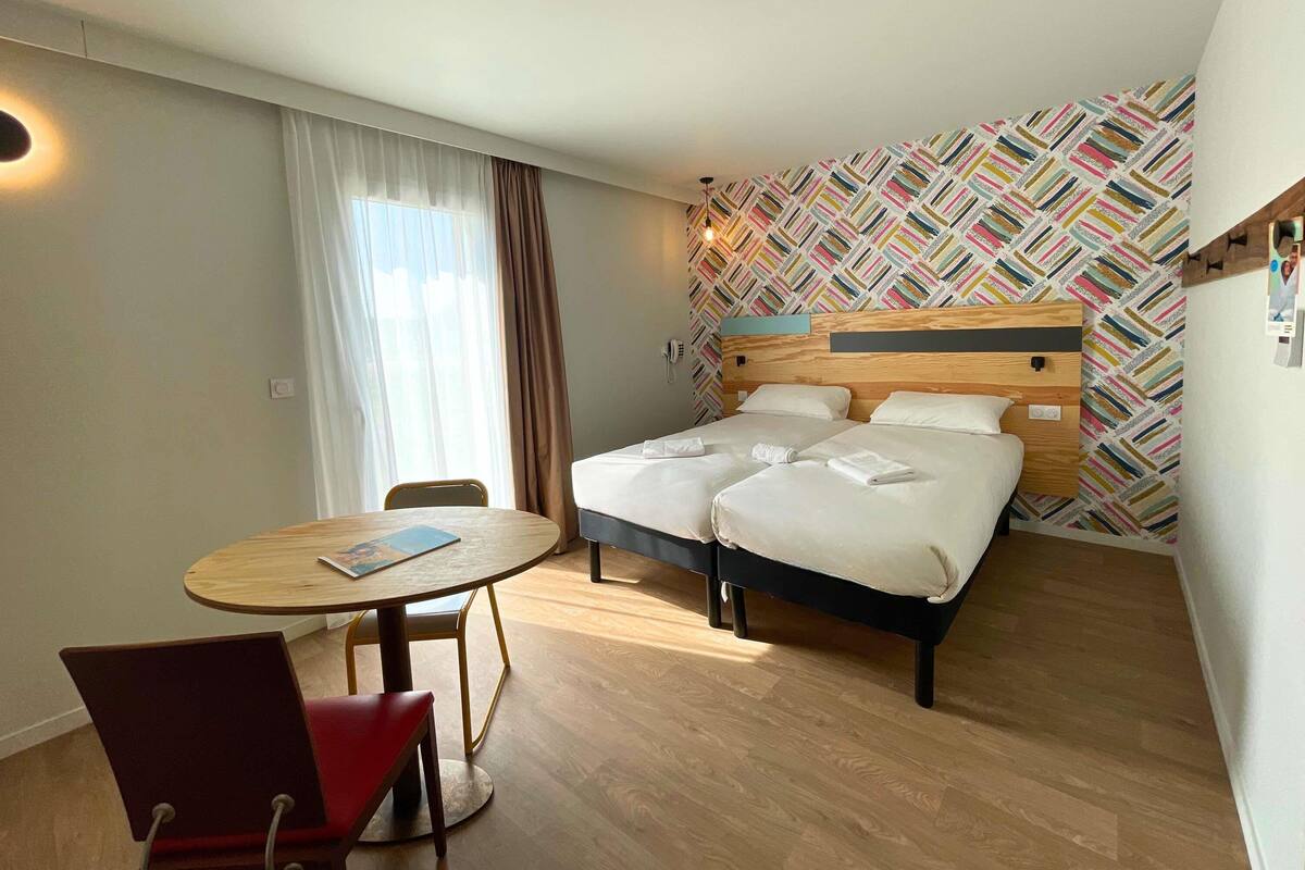A hotel room with a bed, a round table, and a chair.