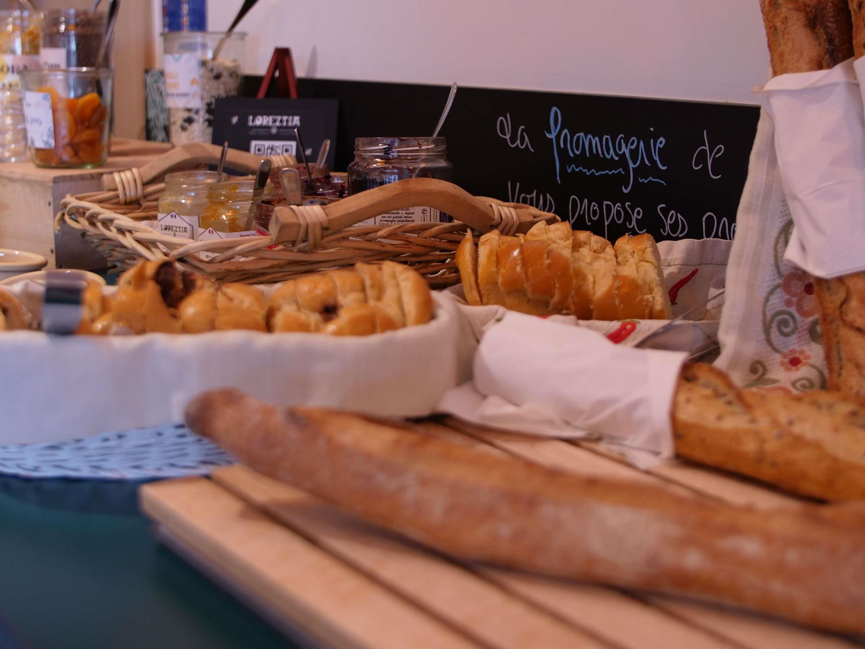 Verschiedene Brotsorten und Gebäck auf einem Holztisch, im Hintergrund ein Schild.