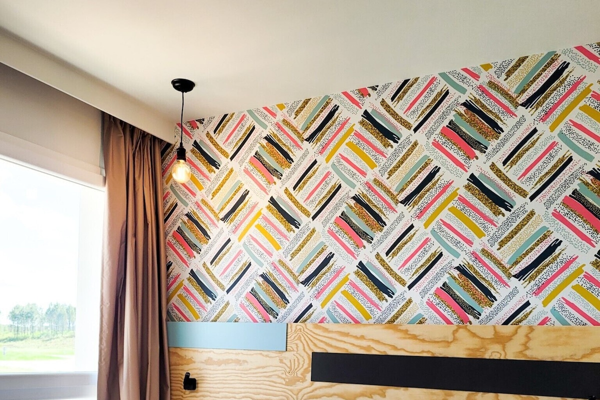 A bedroom with a patterned wallpaper, a wooden headboard, and a large bed with white linens.