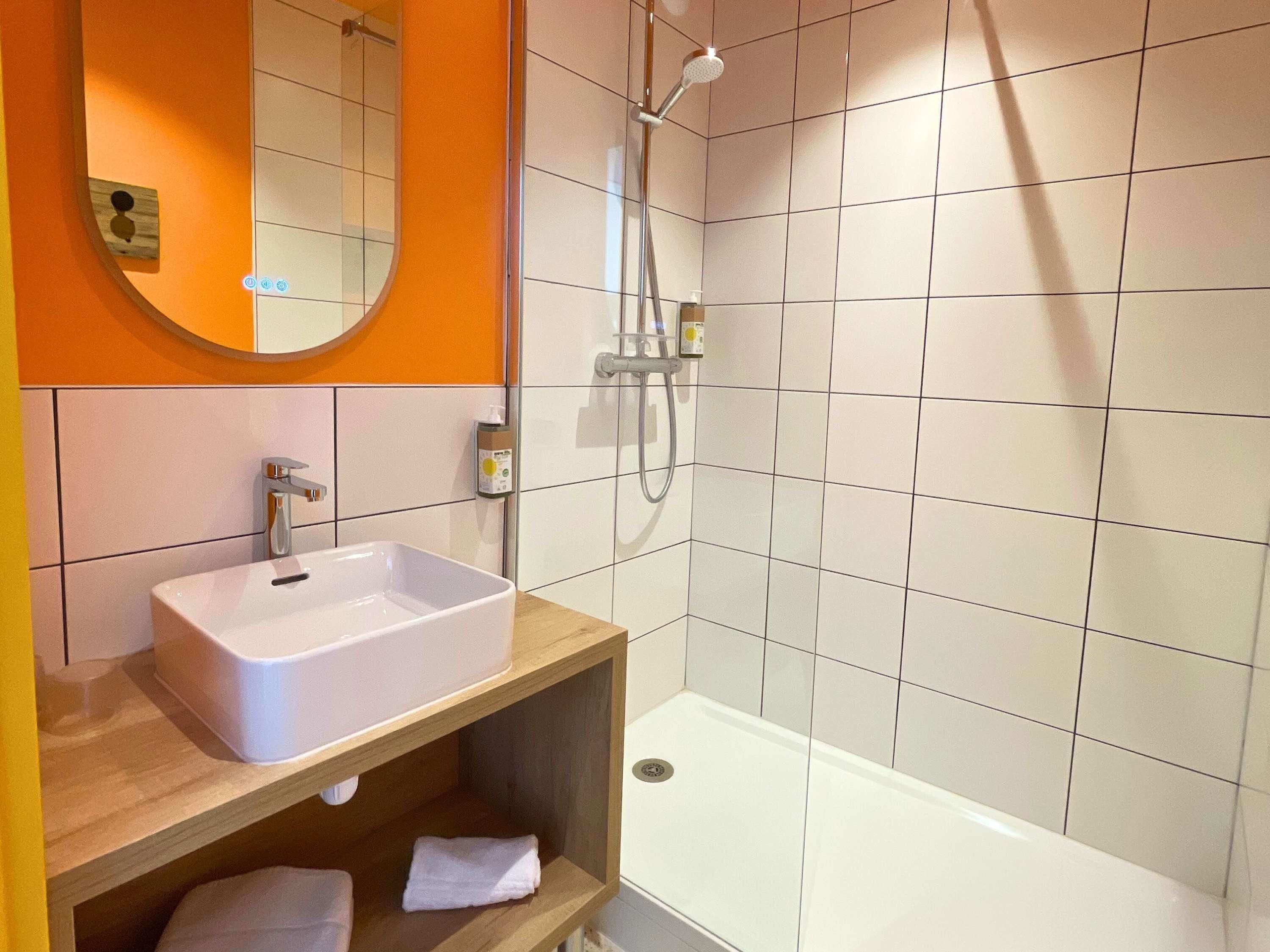 A bathroom with a white sink, a mirror, and a shower.