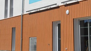A building with a large mural depicting people on a bicycle and a boat, a wooden facade, and a clear blue sky. - greet hotel Castets Coeur des Landes (Castets)