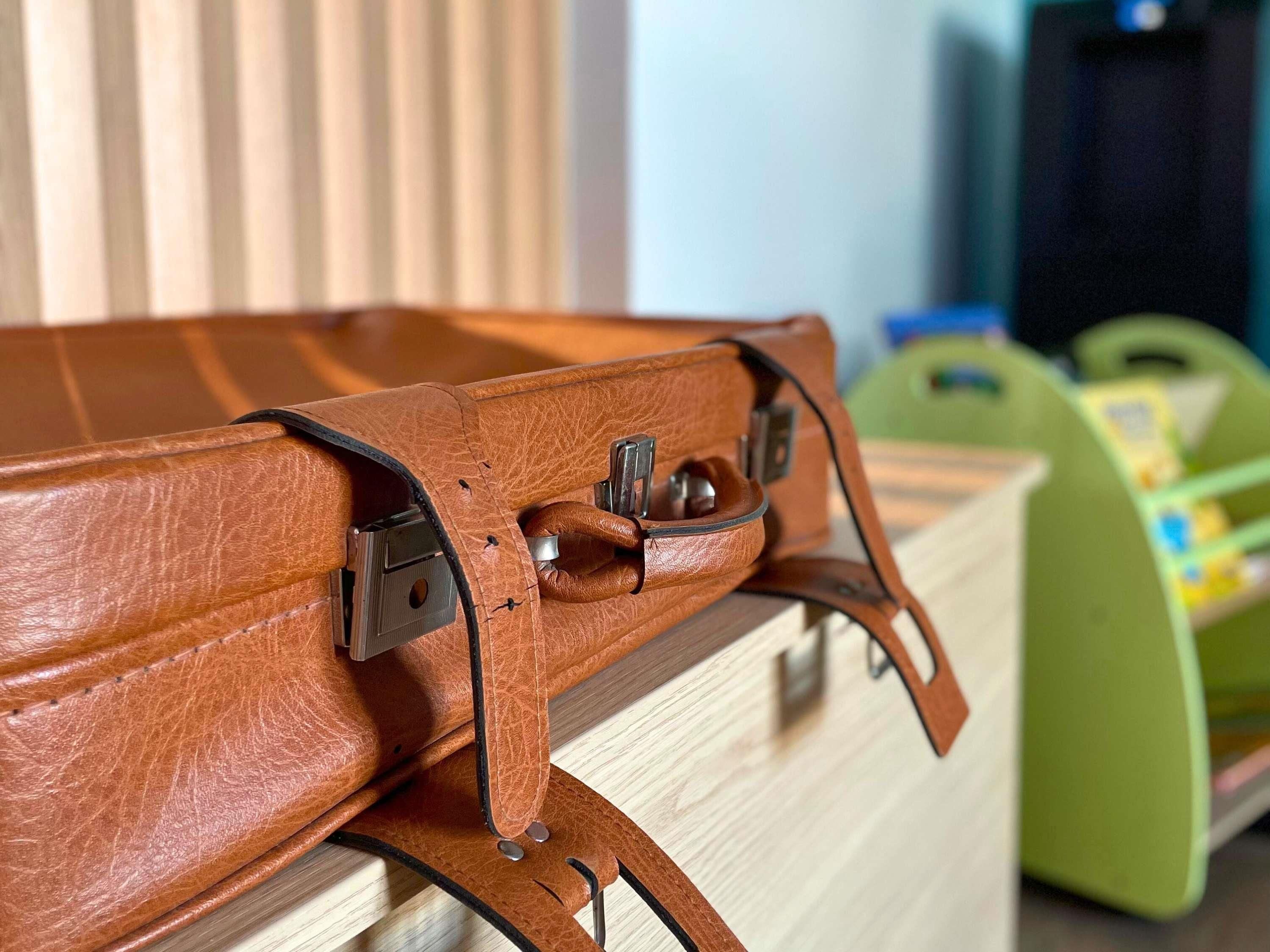 A brown leather bag with metal clasps and a wooden structure.