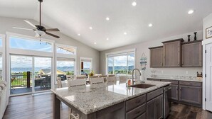 A spacious kitchen with a large island, dark wood cabinets, and a view of the outdoors. - Bear Lake Getaway |Sleeps 19, Hot Tub, Views, Ideal Beach, Ping-Pong! (Garden City)