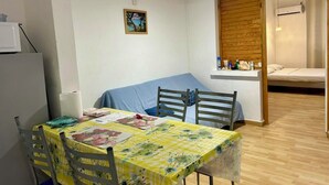 A compact room with a dining table, chairs, a bed, and a small kitchenette area. - Azur apartment with sea view (Sainte-Anne)