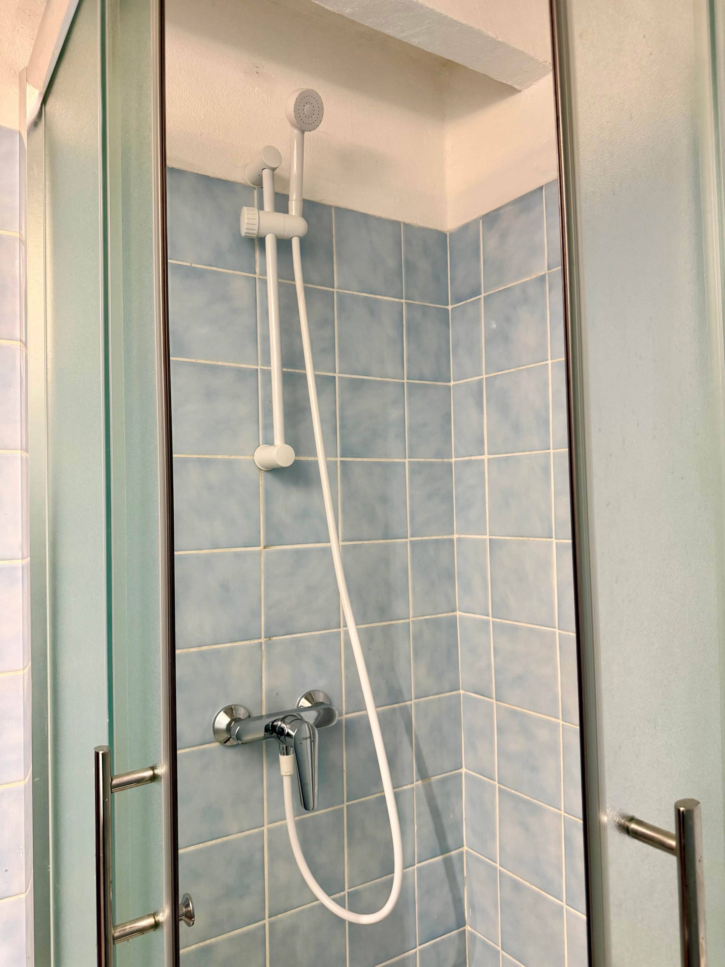 A shower with a handheld showerhead and a fixed showerhead, both mounted on the wall.