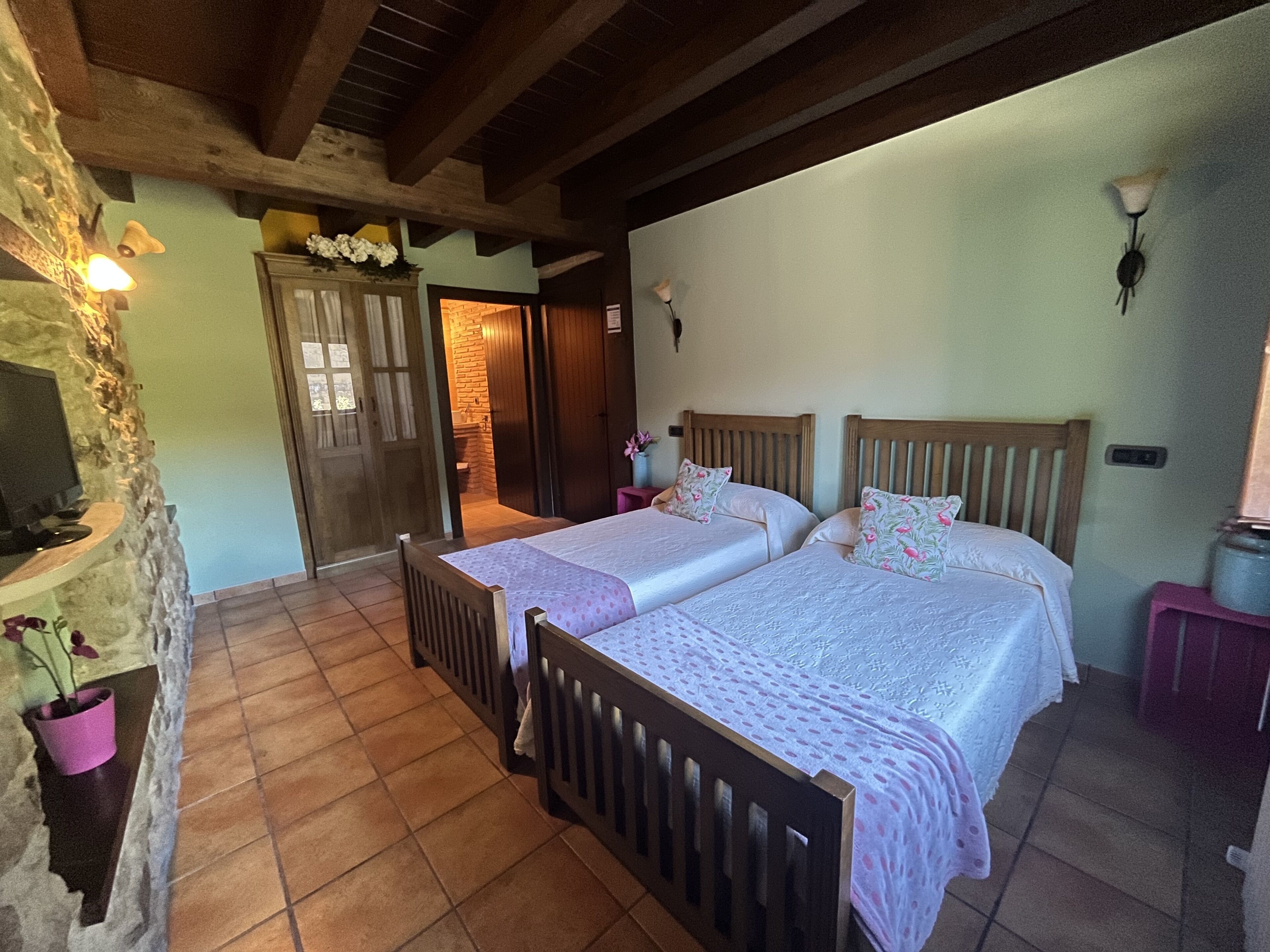 Una habitación con dos camas de madera, una pared de piedra y un techo de madera.