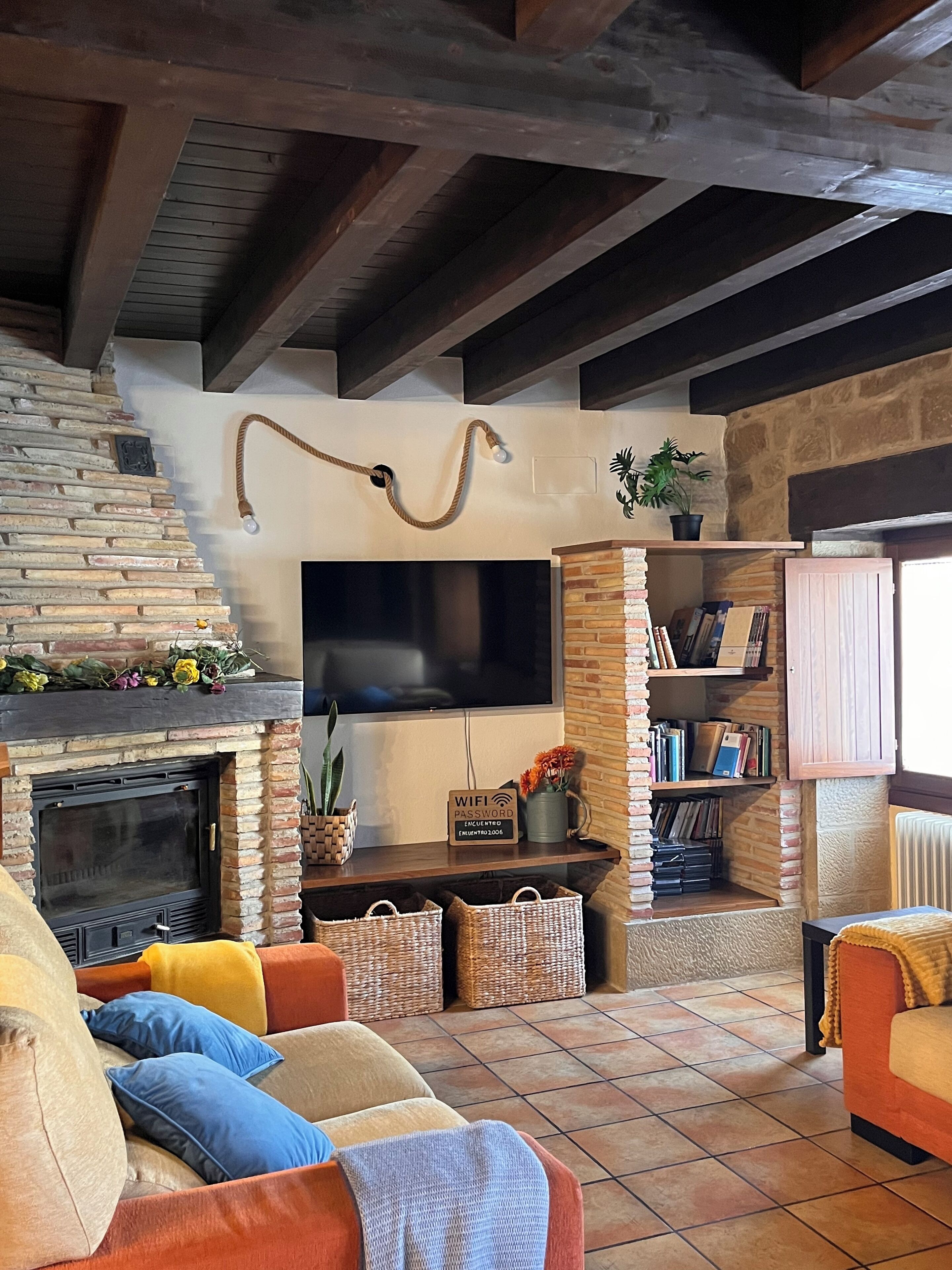 A cozy living room with a fireplace, a flat-screen TV mounted on the wall, and a bookshelf filled with books.