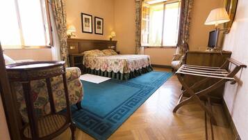 Una habitación con cama, escritorio, silla, mesa y ventana con cortinas.