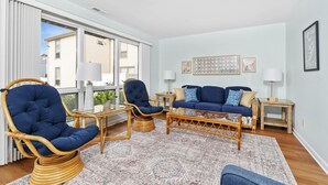 A living room with a blue sofa, two blue armchairs, a coffee table, and a patterned rug. - 215 Cedar Street Unit 4 Rose Garden - Lewes Beach (Lewes)