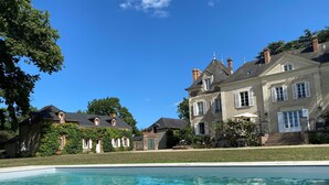 Una casa grande de dos pisos con piscina al frente.