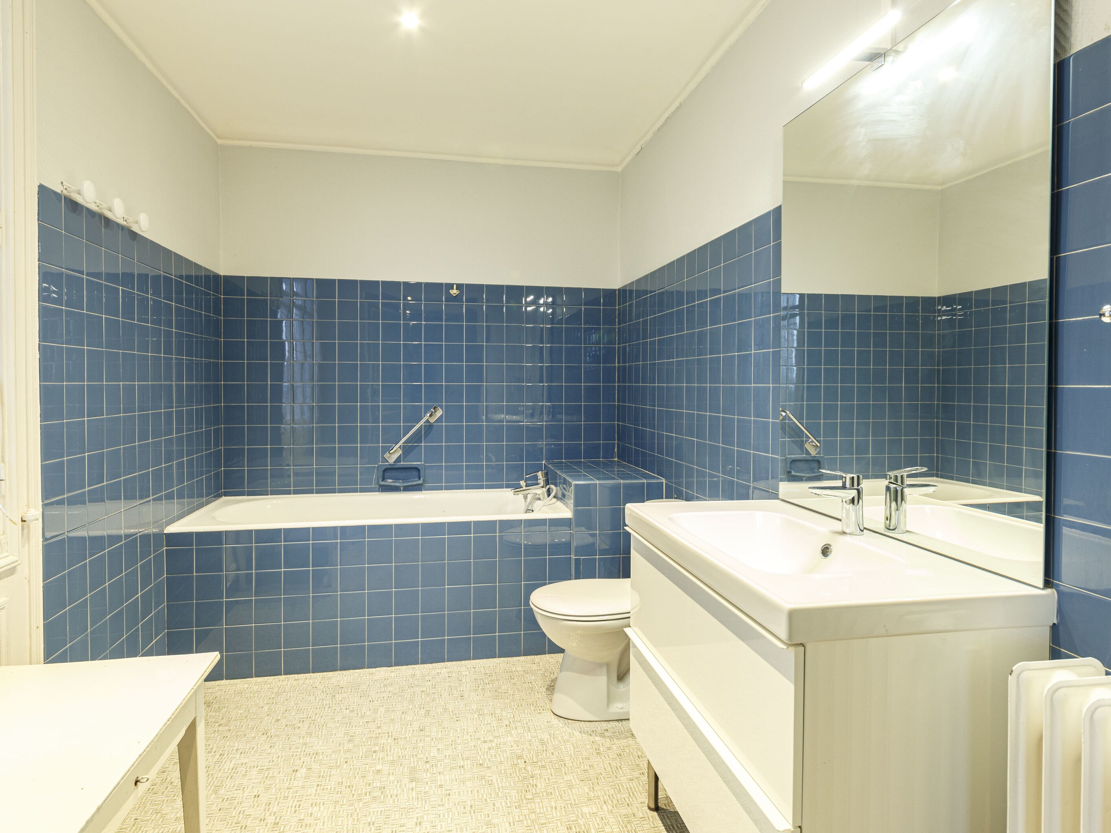 A bathroom with a bathtub, toilet, and vanity with a mirror.